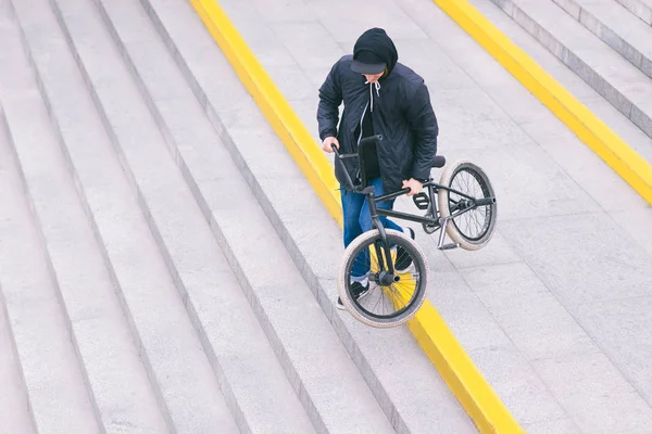 Um adolescente de bicicleta BMX elegante desce as escadas. Caminha com uma bicicleta. Cultura BMX — Fotografia de Stock