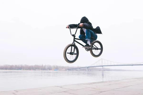 BMX freestyle. The toddler jumps on a BMX bike. BMX rider makes tricks on the background of the river — Stock Photo, Image