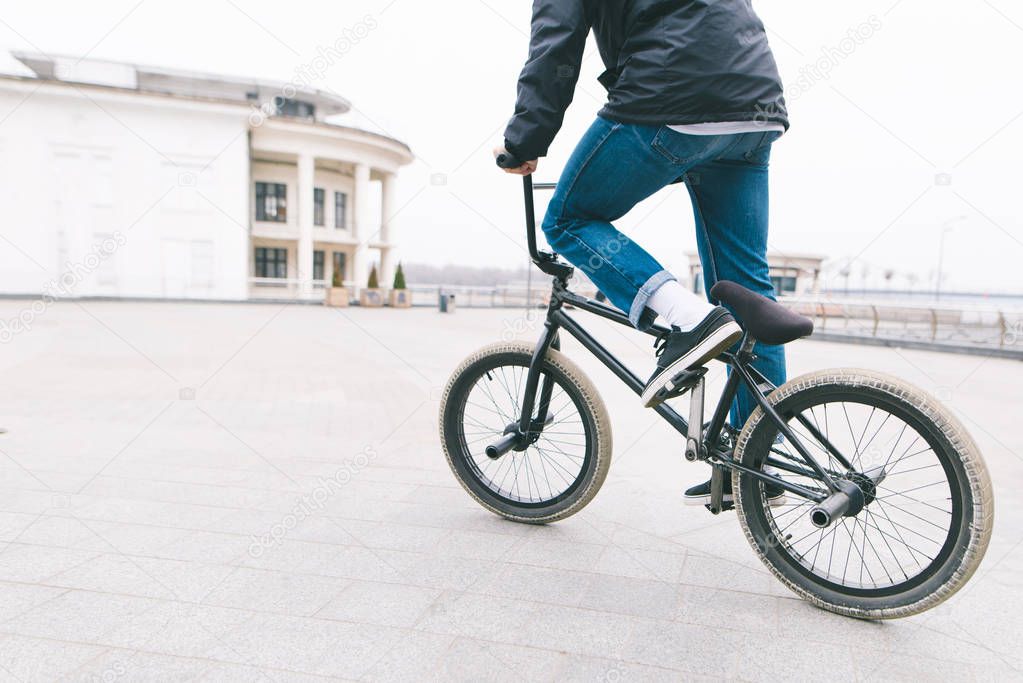 A cyclist rides on BMX in the square. A teenager rides a bicycle in the city. BMX concept