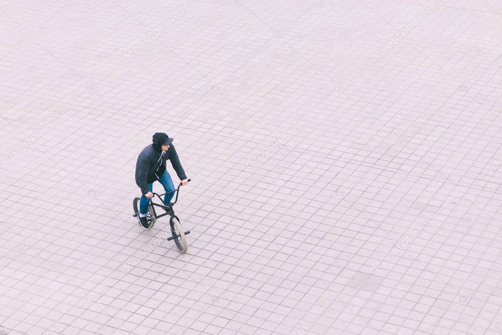 Minimalist photo of a teenager riding a BMX bike. Top view.