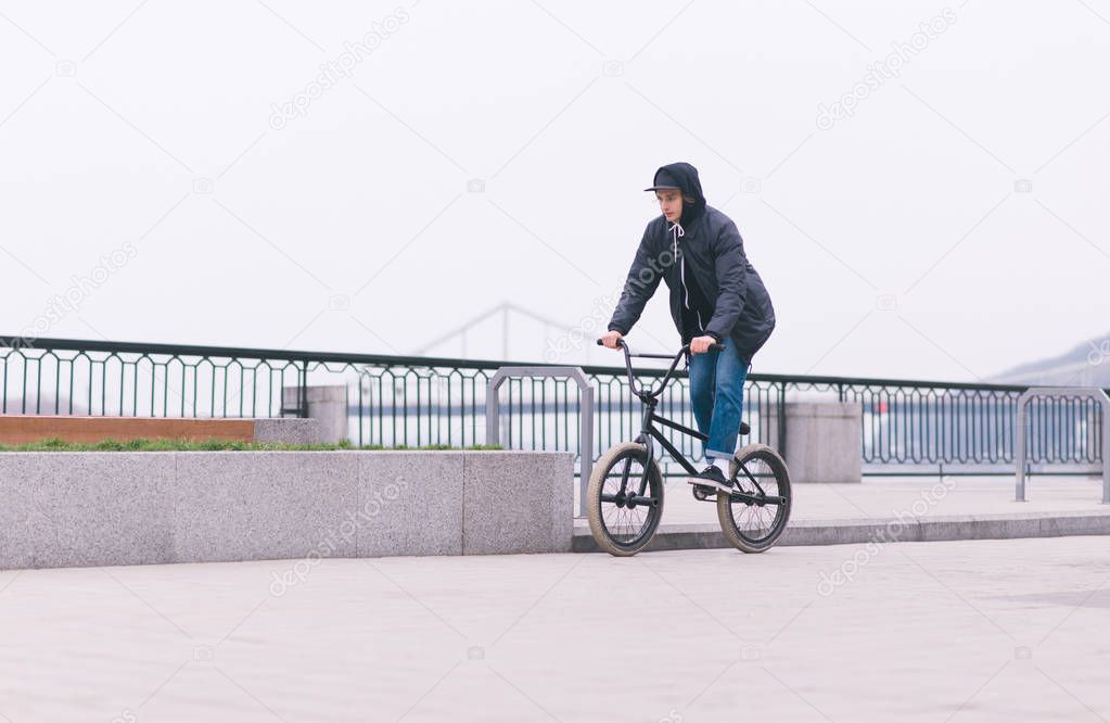 Stylish BMX cyclist travels along the waterfront. Walk on BMX in the city. BMX concept. Street culture