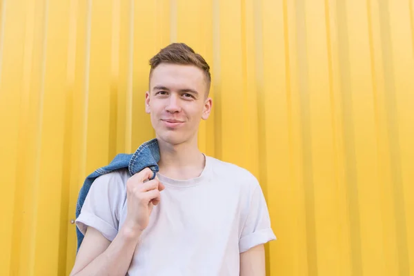 Portrait d'un jeune homme heureux dans un T-shirt blanc sur le fond d'un mur jaune. Un étudiant souriant se tient sur un fond jaune — Photo