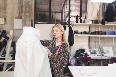 Genç terzi bir kukla giysiler giyiyor. Güzel bir kız giysi moda Studio'da oluşturur. Terzi kavramı