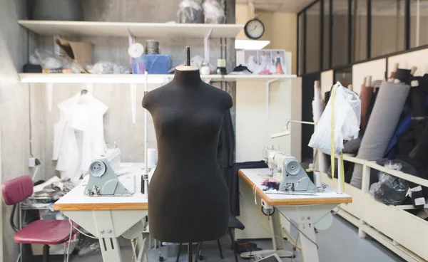 Maniquí negro de pie en el fondo del estudio crear moda. Las costureras del lugar de trabajo - el maniquí, la máquina de coser, la tela. Concepto de negocio de costura . — Foto de Stock
