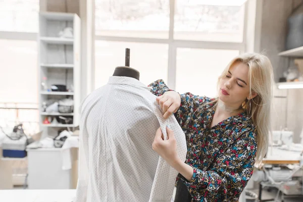 Genç kadın terzi işleri iğneler manken üzerinde giysiler ekler. Moda Tasarımcısı şık giysiler stüdyoda oluşturur. Moda Tasarımcısı kavramı. Elbise üzerinde odaklanmak — Stok fotoğraf
