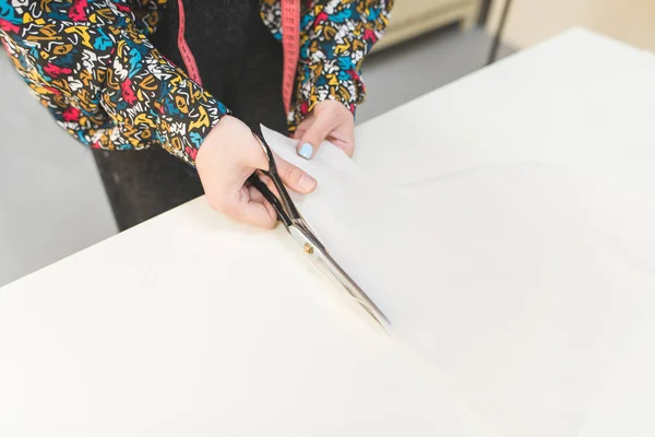 As mãos da costureira cortam a tesoura em uma mesa branca. Conceito de costura.Copyspace Imagens De Bancos De Imagens Sem Royalties