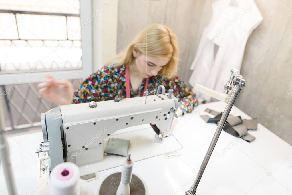 Abstract photo of a young seamstress on a sewing machine. Dressmaker work on the sewing machine. Sewing business concept.