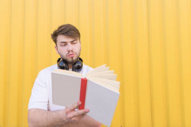 Bir öğrenci sarı bir arka plan üzerine bir kitap okur. Yakışıklı bir adam bir kitap ile sarı bir duvar ve okuma arka plan üzerinde duruyor