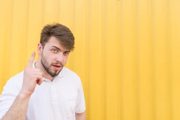 Hombre guapo muestra un pulgar hacia arriba sobre un fondo amarillo. En un hombre con una idea en el fondo de una pared amarilla. Texto para texto. Espacio de copia — Foto de Stock