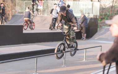 Genç bir adam Bmx Bisiklet arka planda bir skate Park üzerinde hile yapıyor. Bir grup insan bir skate Park Bmx ile eğitim Bmx.