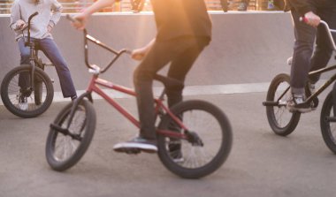 Günbatımında bir skate Park Bmx bisiklet üzerinde gençler bir grup. Bacakları ve bmx gün batımında. BMX kavramı
