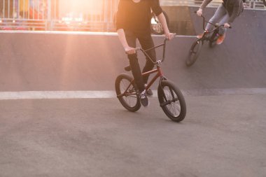 Gün batımını arka planda bir skate Park Bmx bisiklet sürmek gençler. BMX kavramı. BMX bisiklet eğitim