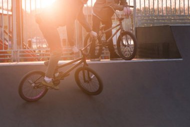 BMX bisiklet güneşin arka plan üzerinde bir rampa skate park binmek. BMX biniciler hile skate Park günbatımında yapmak.