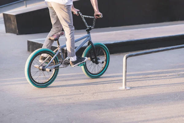 A teenager rides a blue BMX bike on a skate park and is about to make a trick. A young man rides a BMX bike. BMX culture — Stock Photo, Image