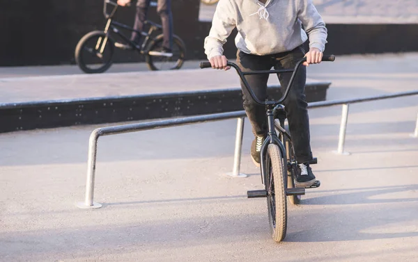 Een groep jonge mensen een skatepark rijden op een bmx fiets en trucs doen. Opleiding trucs over bmx. — Stockfoto