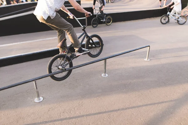 De jonge man voert de Bmx truc op de reling in het vak overslaan. Benen en Bmx uitvoeren een truc. Sporten in een skatepark. BMX concept. — Stockfoto