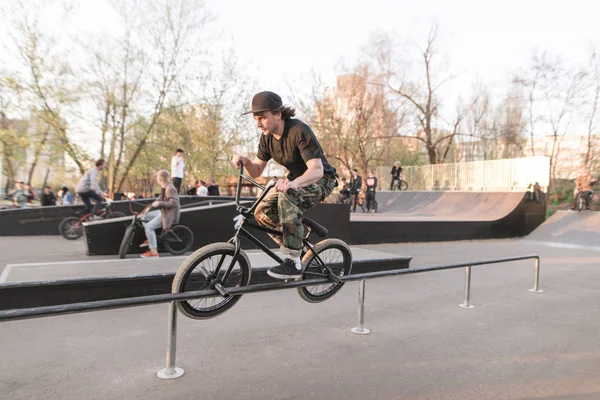 BMX rider realiza un truco en un parque de skate. Entrenamiento en BMX. Concepto BMX. Resbalón en BMX en barandillas —  Fotos de Stock