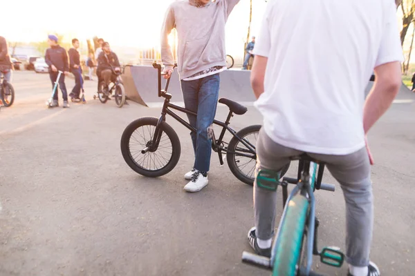 Company bmx riders in a skate park on the background of the sunset. Training young people on a bmx bike. bmx concept