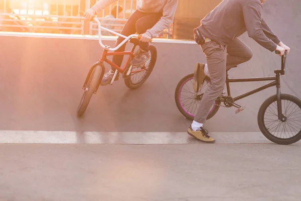 I cavalieri Bmx fanno scherzi in uno skate park sullo sfondo del tramonto. Addestramento serale ciclisti BMX. Concetto Bmx — Foto Stock