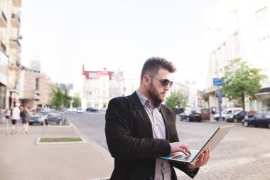 Bir meşgul iş adamı onun elleri ve çalışan bir dizüstü bilgisayar ile sokağın ortasında duruyor. Takım elbiseli bir adam yolda çalışıyor. Son Tarih kavramı.