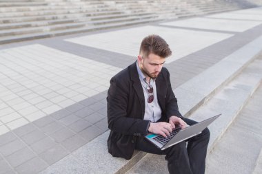 Bir dizüstü bilgisayar açık havada üzerinde çalışan iş adam. Merdivenlerde oturan ve bir dizüstü bilgisayar üzerinde çalışan bir adam portresi. Son Tarih.