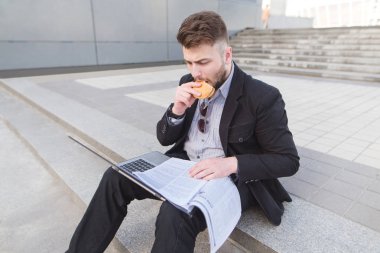 Onun kucak ve aperatifler bir dizüstü bilgisayar ve belgeler ile yere meşgul adam oturur. Merdivenlerde oturan, çıplak bir havlu üzerinde çalışma ve yeme işadamı