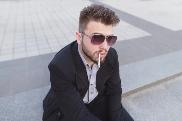 Retrato de un hombre de negocios guapo con un cigarrillo en la boca. Un hombre de negocios elegante fuma un cigarrillo de cerca — Foto de Stock