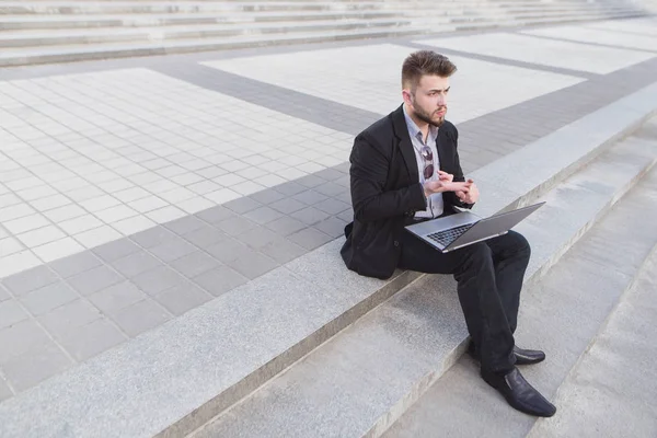 Занятой человек, сидящий на лестнице и работающий над ноутбуком. Работай на улице. Крайний срок. Концепция бизнеса — стоковое фото