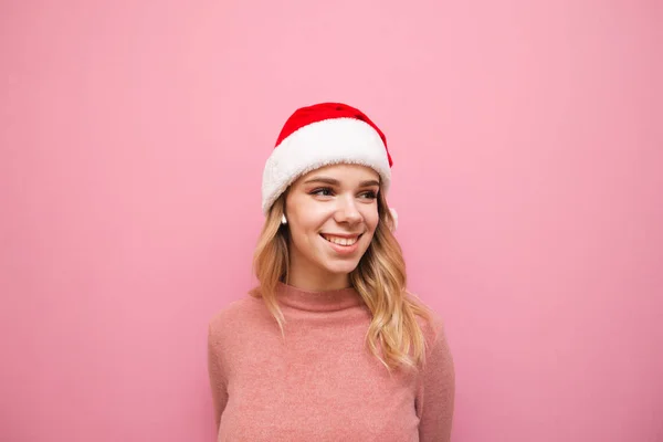 분홍색 스웨터와 크리스마스 모자를 입은 귀여운 소녀의 사진, 무선 헤드폰으로 음악을 듣는 모습, 빈 공간을 바라보는 모습, — 스톡 사진