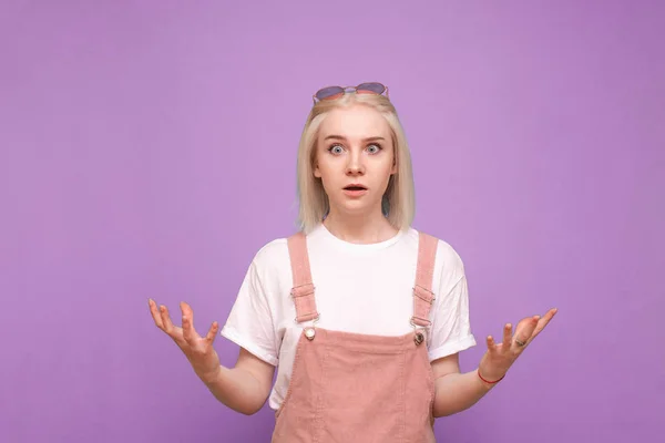 Shocked girl teenager is isolated on a purple background and loo