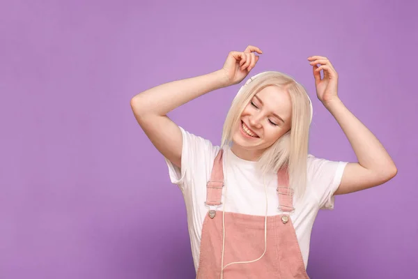 Šťastná dívka blond dívka poslouchá hudbu ve sluchátkách s očima c — Stock fotografie