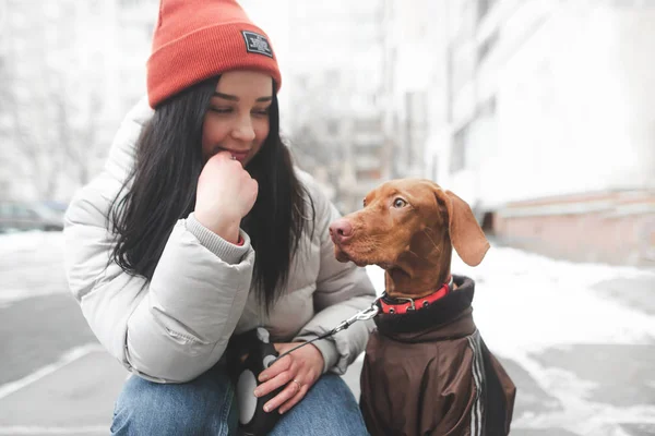 Attractive woman in warm clothes sitting on the street with a do