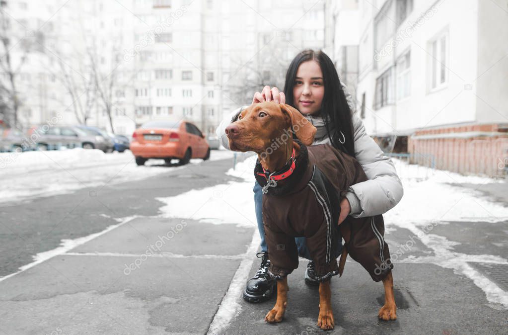Beautiful girl in warm clothes with a beautiful dog sitting in t