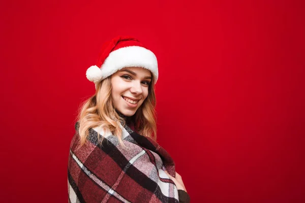 Retrato de uma menina bonito em um chapéu e xadrez em um fundo vermelho, olhando para a câmera e sorrindo. Menina positiva desfrutando xadrez no inverno no Natal. X-mas — Fotografia de Stock