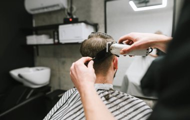 Creating a close-up of a man's haircut, a hairdresser cuts his hair with a haircut and a comb. Barber's hands and work on client's hair. Background. Barber shop concept. Men's haircuts