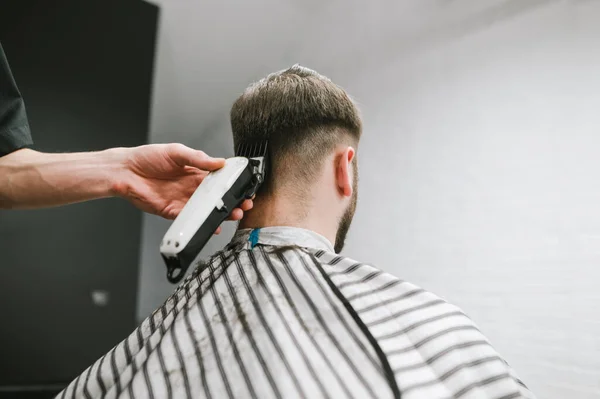 Friseur macht dem Mann mit einem Trimmer eine Frisur. Friseur schneidet den Kunden. Hand mit einem Haarschneider rasiert Haare vom Hinterkopf. Einsatz von Clipper. — Stockfoto
