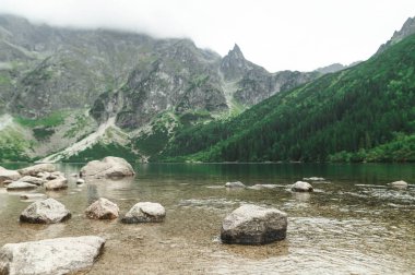 Güzel, büyük bir dağ gölünde kayalar ve berrak su. Tatra Ulusal Parkı, Morskie Oko. Tatra Dağları. Uzayı kopyala Arkaplan.