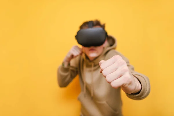 Un boxeur sur fond jaune avec un casque VR sur la tête. Isolé. Gros plan et Concentrez-vous sur le poing. Jeune homme jouant à des jeux VR. Isolé. Jeux de réalité virtuelle . — Photo