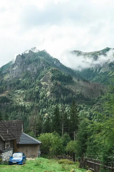 Dağ manzarasının arka planında arabası olan bir kulübe. Güzel Tatra Dağları ve ahşap ev. Dağlardaki kır evi.. — Stok fotoğraf