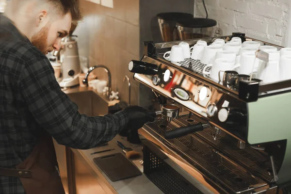 Mannelijke barista bereidt koffie in de coffeeshop. Bebaarde cafe eigenaar is het maken van koffie drinken op koffiemachine. — Stockfoto
