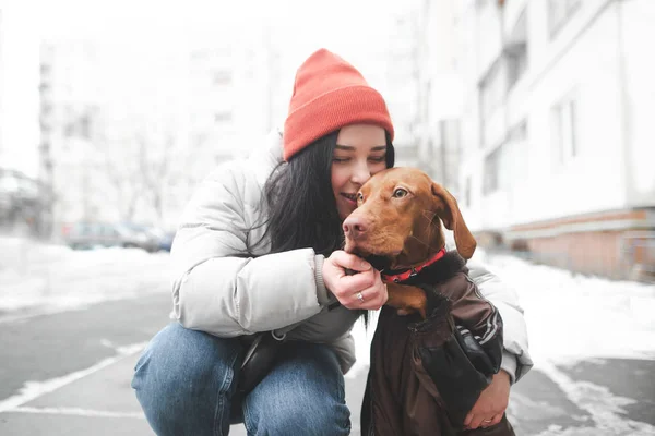 Boldog lány megölel és megcsókol egy gyönyörű narancssárga kutyát a hátán. — Stock Fotó