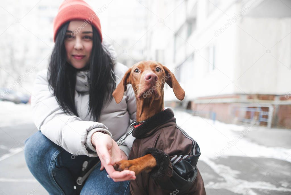 Portrait of a smiling girl and a dog in warm clothes sitting in 