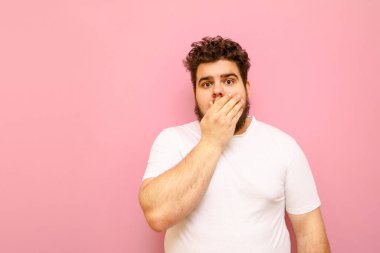 Aşırı kilolu adamın pembe arka planda durmasına şaşırdım. Ağzını kapadı ve kameraya baktı. Şişko, komik, kıvırcık suratlı, ağzını kapatan genç bir adam..