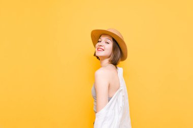 Sarı arka planda izole edilmiş, kameraya bakıp gülümseyen mutlu kız portresi. Şapkalı ve tişörtlü pozitif bayan turist turuncu arka planda duruyor. Anlaşıldı.