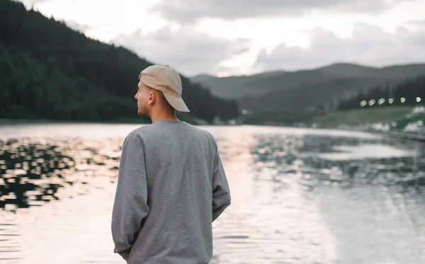 Молодой Человек Кепке Стоит Озере Горах Смотрит Красивый Пейзаж Вид — стоковое фото