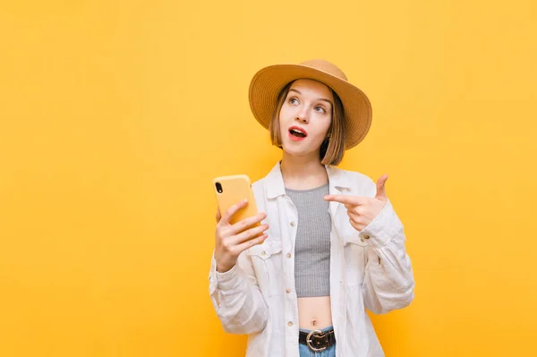 Chica Expresiva Sombrero Muestra Dedo Teléfono Inteligente Mira Hacia Otro — Foto de Stock