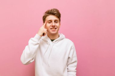Gülümseyen genç adam parmağını şakağına koyar ve bir 