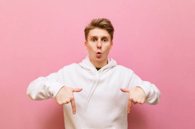 Şaşırmış genç sarışın adam boş alana bakıyor ve parmaklarını işaret ediyor. Şaşırmış suratlı duygusal adam fotokopi odasında kendini soyutlamış..