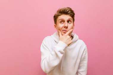 Beyaz günlük giysiler içinde komik düşünceli bir adam pembe arka planda duruyor, komik suratlı boş bir noktaya bakıyor. Cesetli genç adam başka yere bakar ve düşünür, pembe üzerinde soyutlanmış. Boşluğu kopyala