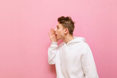 Hafif gündelik giysiler içinde yakışıklı bir genç yana bakar ve avuç içi açık bağırır. Genç sarışın adam fotokopi odasında konuşuyor, pembe üzerinde isolvajik.